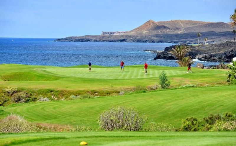 Golfers on the green on an oceanside hole on Tenerife's Amarilla Golf